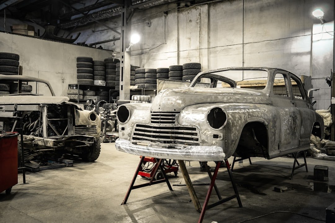 Vintage cars lined up inside a restoration workshop with overhead lighting