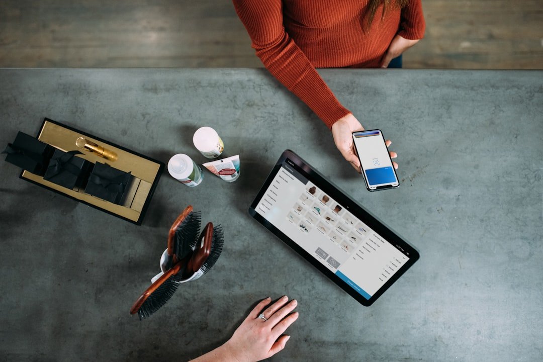 Overhead view of a retail workspace with a smartphone, tablet, and coffee cups on a white table
