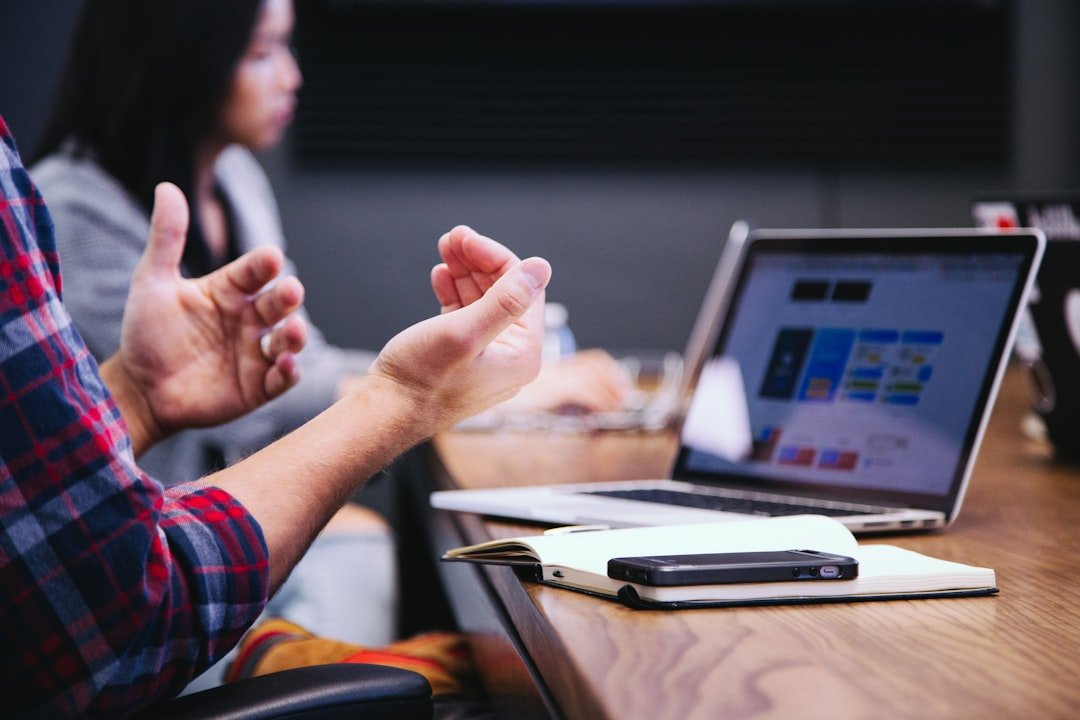 Person gesturing and presenting ideas during a strategy meeting with a laptop on the table