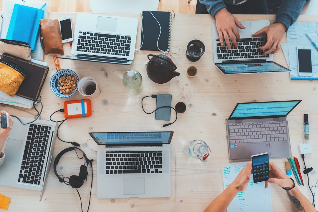Team of developers sitting around a table with multiple open laptops in a modern office
