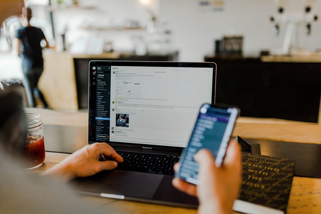 Person multitasking with a smartphone and laptop open to a team collaboration app