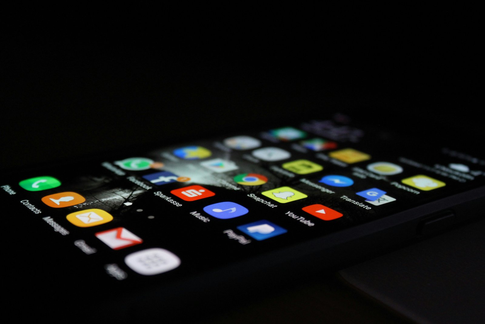 Android smartphone angled on a dark surface, home screen showing rows of colorful app icons