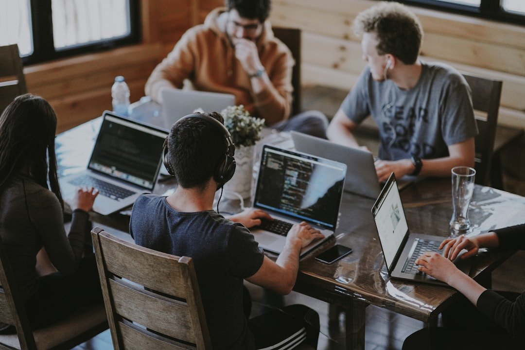 Group of colleagues working together on laptops around a shared office table