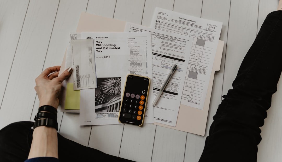 Person holding financial planning papers beside a pen and calculator on a desk