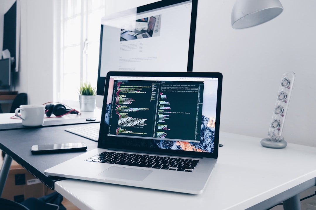 MacBook laptop displaying lines of code on a cluttered developer desk